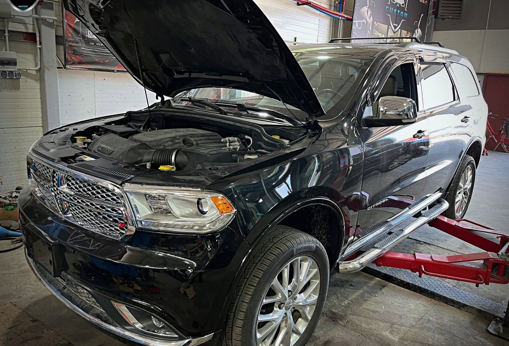 Czarny Dodge Durango z otwartą maską na podnośniku w warsztacie HiTune